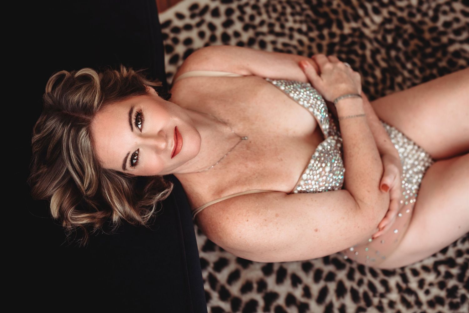 Artistic boudoir photography on leopard print background with dramatic lighting and poses.
