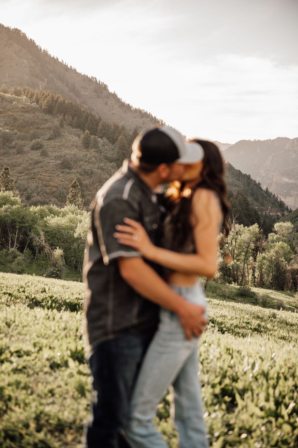 Candid romantic moments photographed against mountain landscape at sunset.