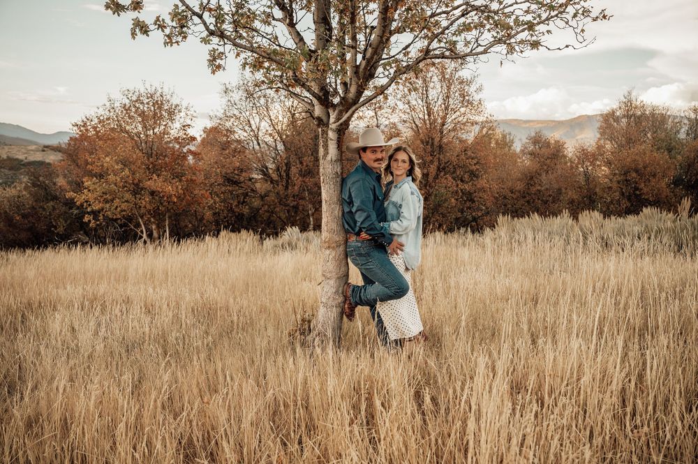 Autumn field engagement session with tall golden grass and trees in background.