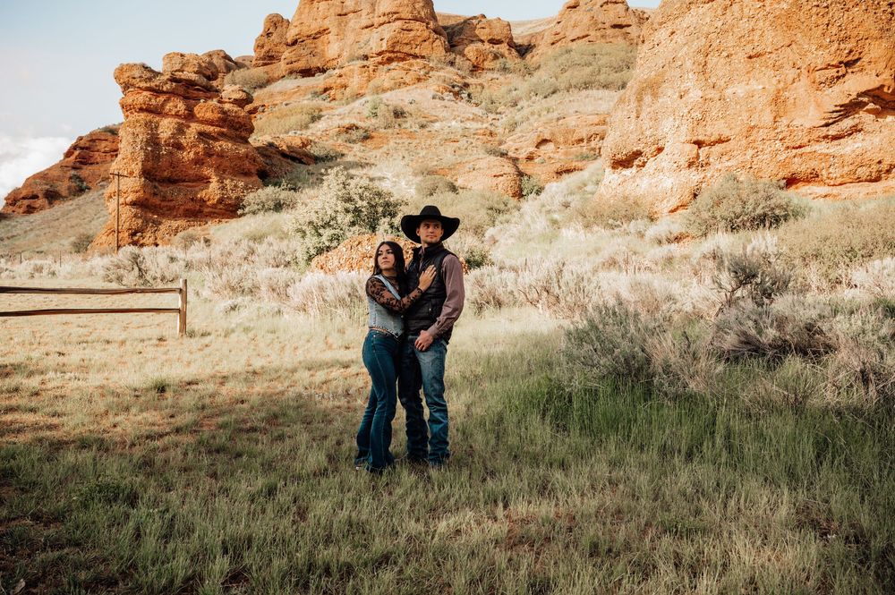 Couple poses for romantic photos against stunning red rock formations in desert landscape.