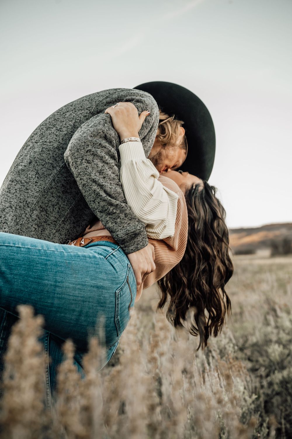 Artistic countryside photoshoot showing romantic embrace against natural desert backdrop.