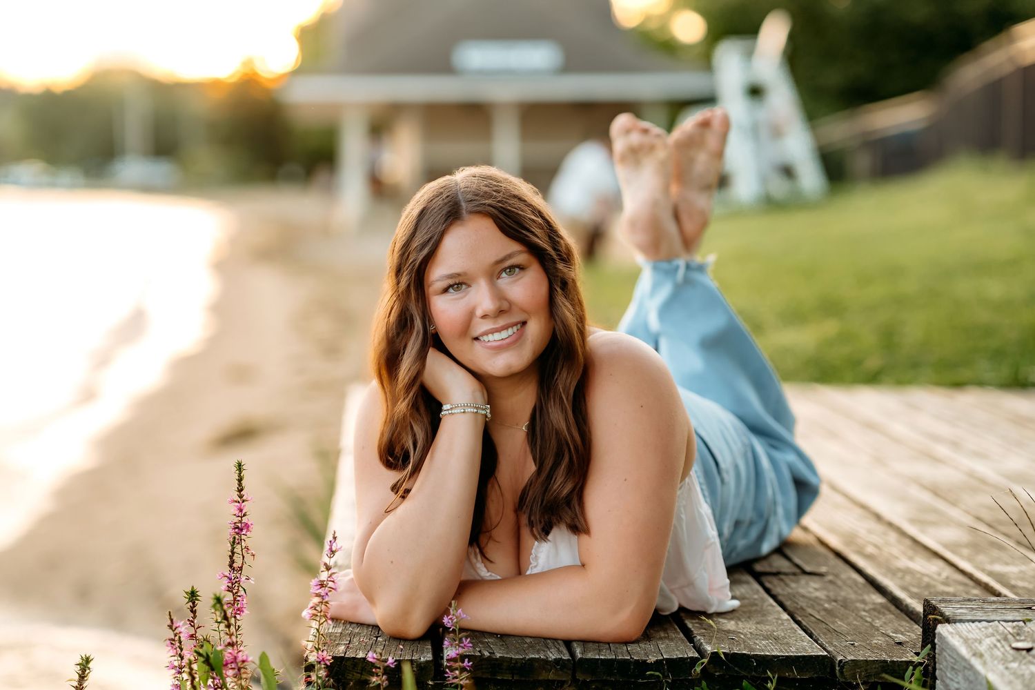 A person lies on a wooden deck during a golden sunset photo session in a park setting.