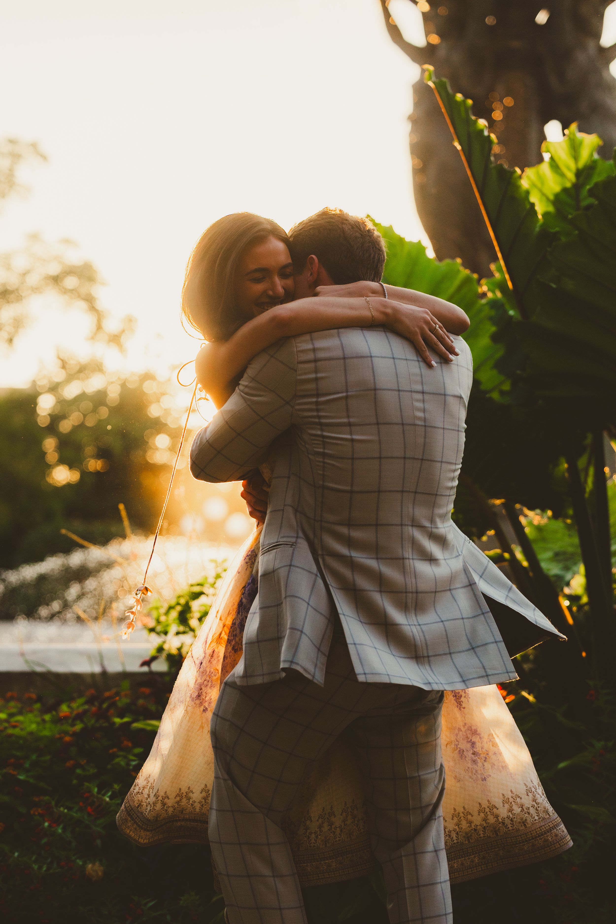 A romantic couple embraces in a sunlit garden during golden hour at the Bartholdi Fountain