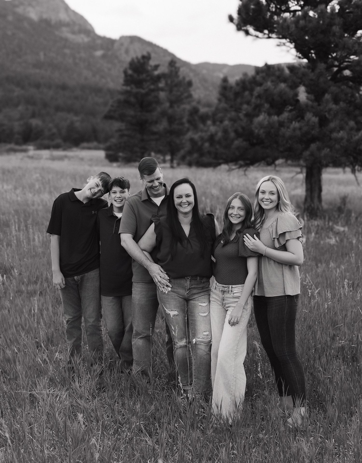 A series of black and white photos showing tender family moments outdoors during a sunset photo session.