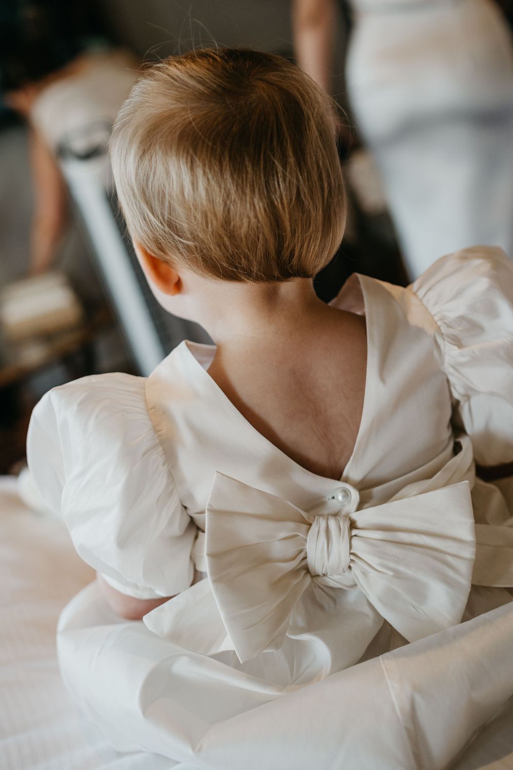 Close-up view of a white satin dress with an oversized bow detail on the back.