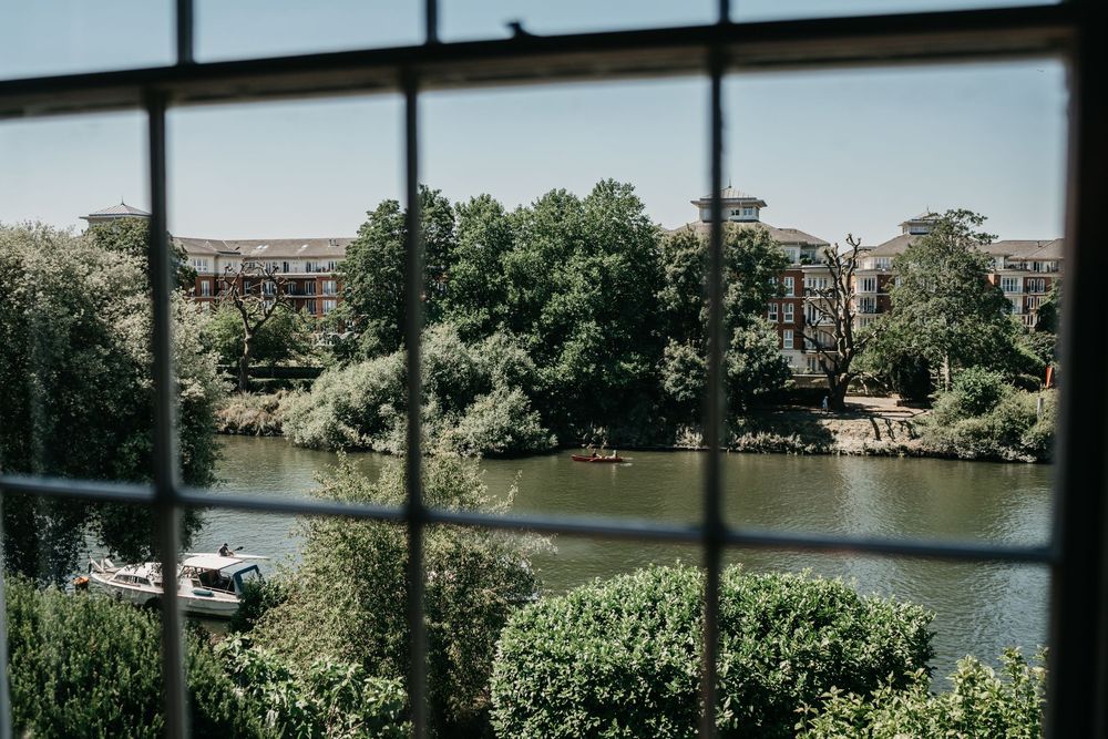 Scenic river view with lush green vegetation along the banks and a bridge visible in the distance.