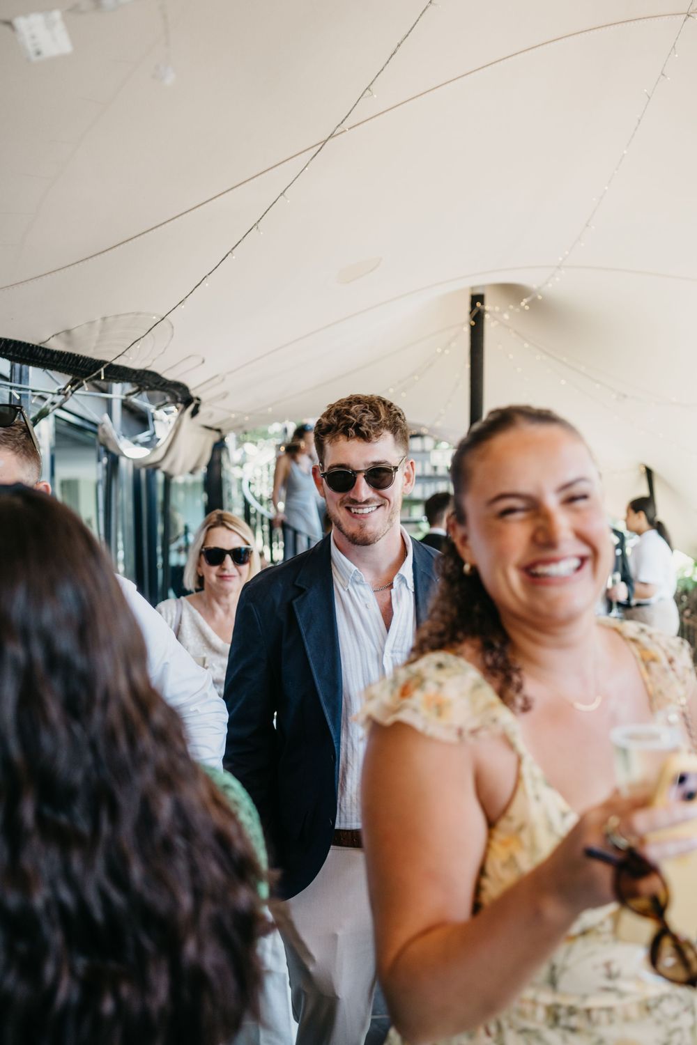 Candid moments of laughter and joy captured during a wedding celebration with guests in sunglasses and formal attire.
