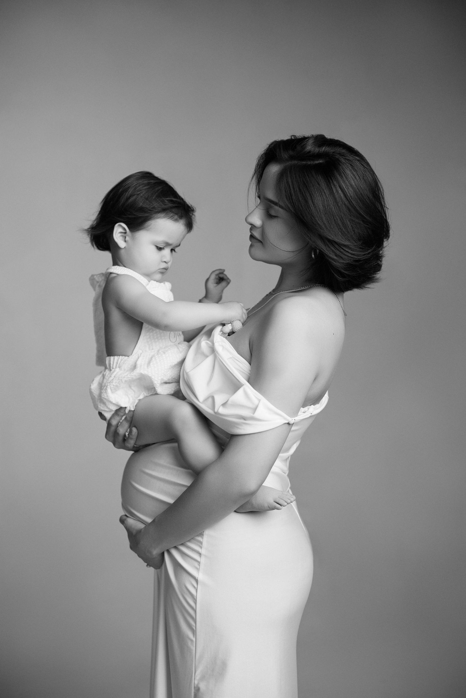 Black and white portraits of mother and baby in matching white outfits.