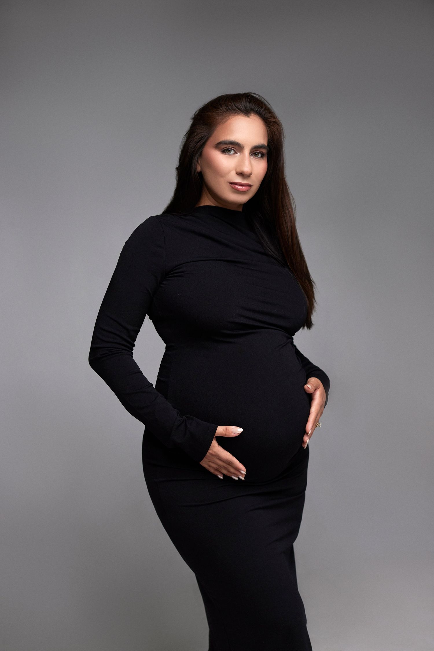 Woman in black turtleneck poses for dramatic maternity photos.