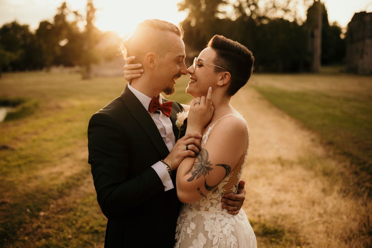 Newlyweds share passionate moment in golden sunset light.
