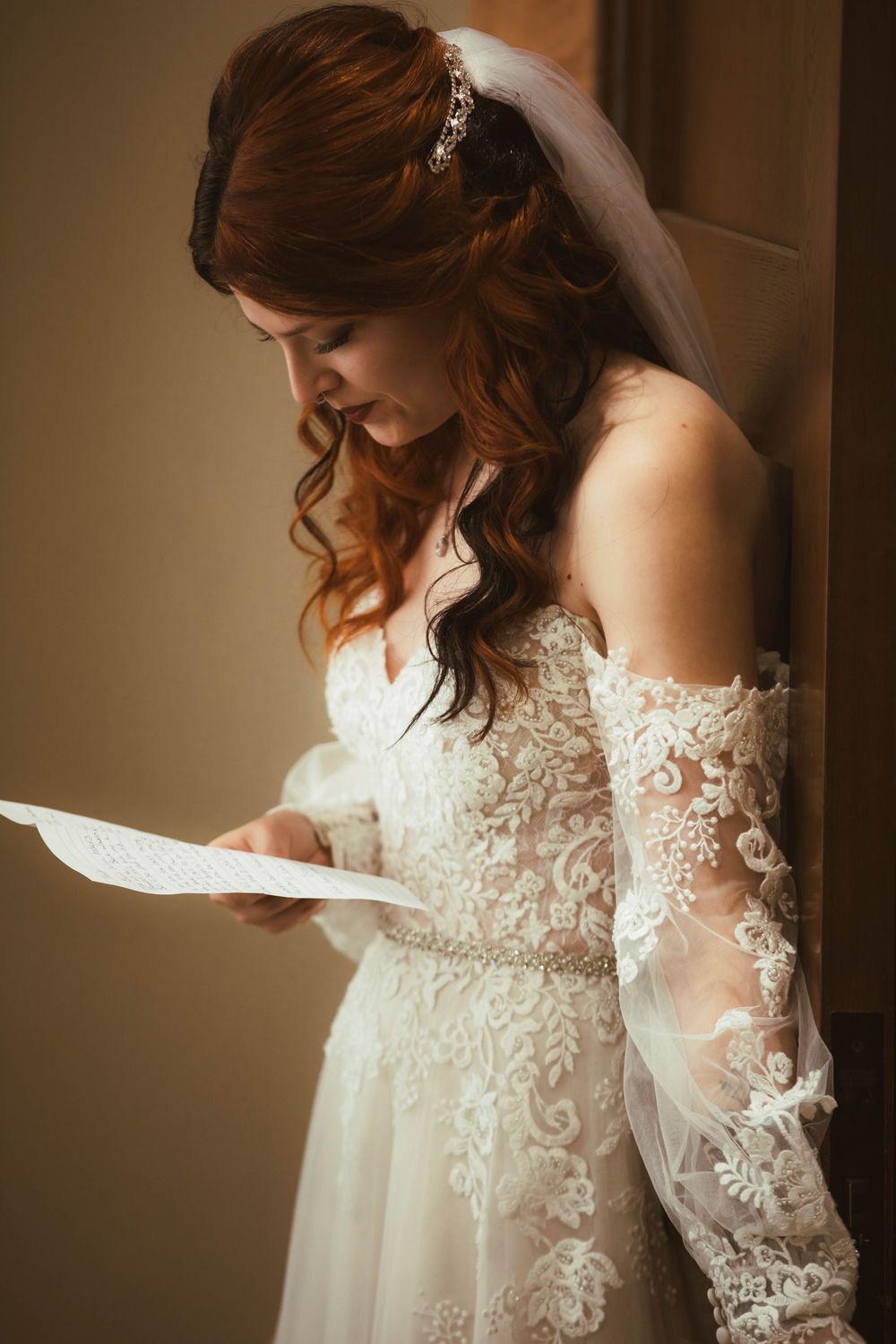 A delicate lace wedding dress with intricate details and flowing sleeves captured in a warm, romantic light.
