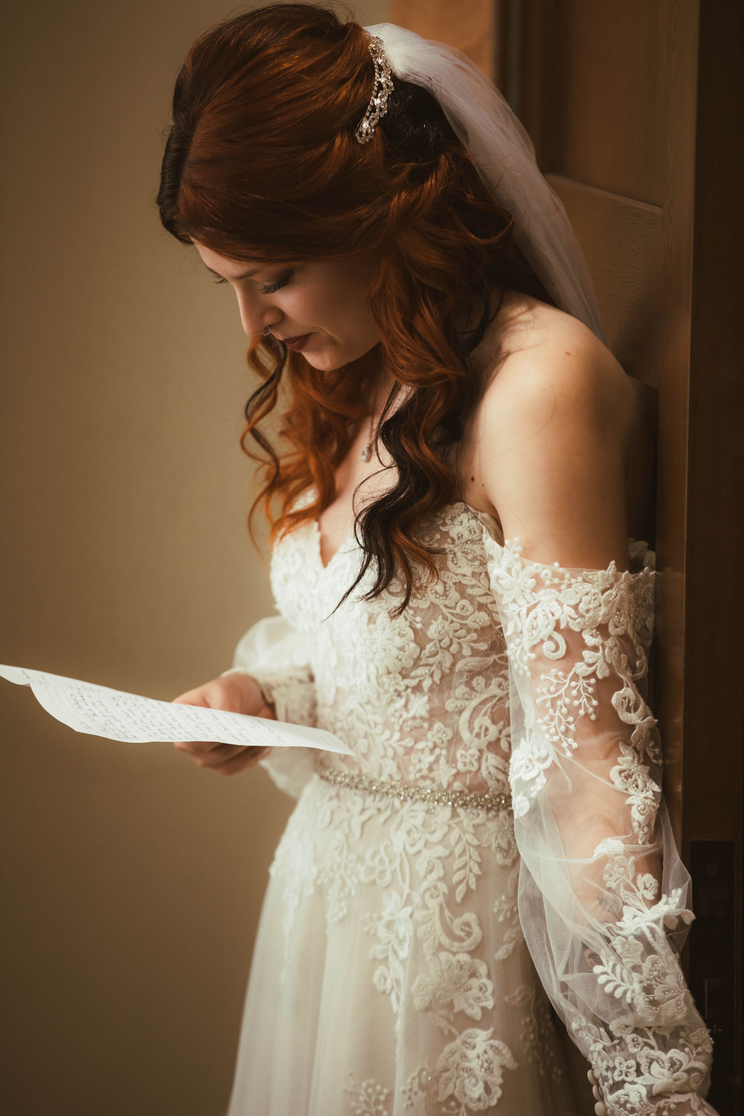A delicate lace wedding dress with intricate details and flowing sleeves captured in a warm, romantic light.