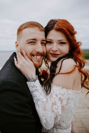 A romantic wedding portrait captured against an overcast sky.