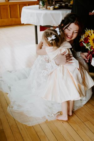 Detail shot of bride's flowing white lace wedding dress on wooden floor.