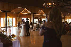Rustic wooden reception venue with white tablecloths and warm lighting creates an elegant wedding atmosphere.