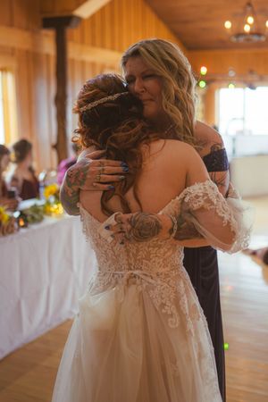 Emotional wedding scene unfolds in a wooden barn venue with natural light streaming through windows.