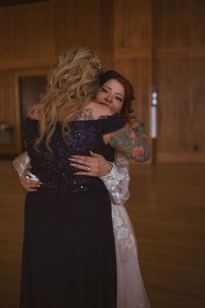 Tender embrace shared between two people at a wedding reception in a rustic venue.