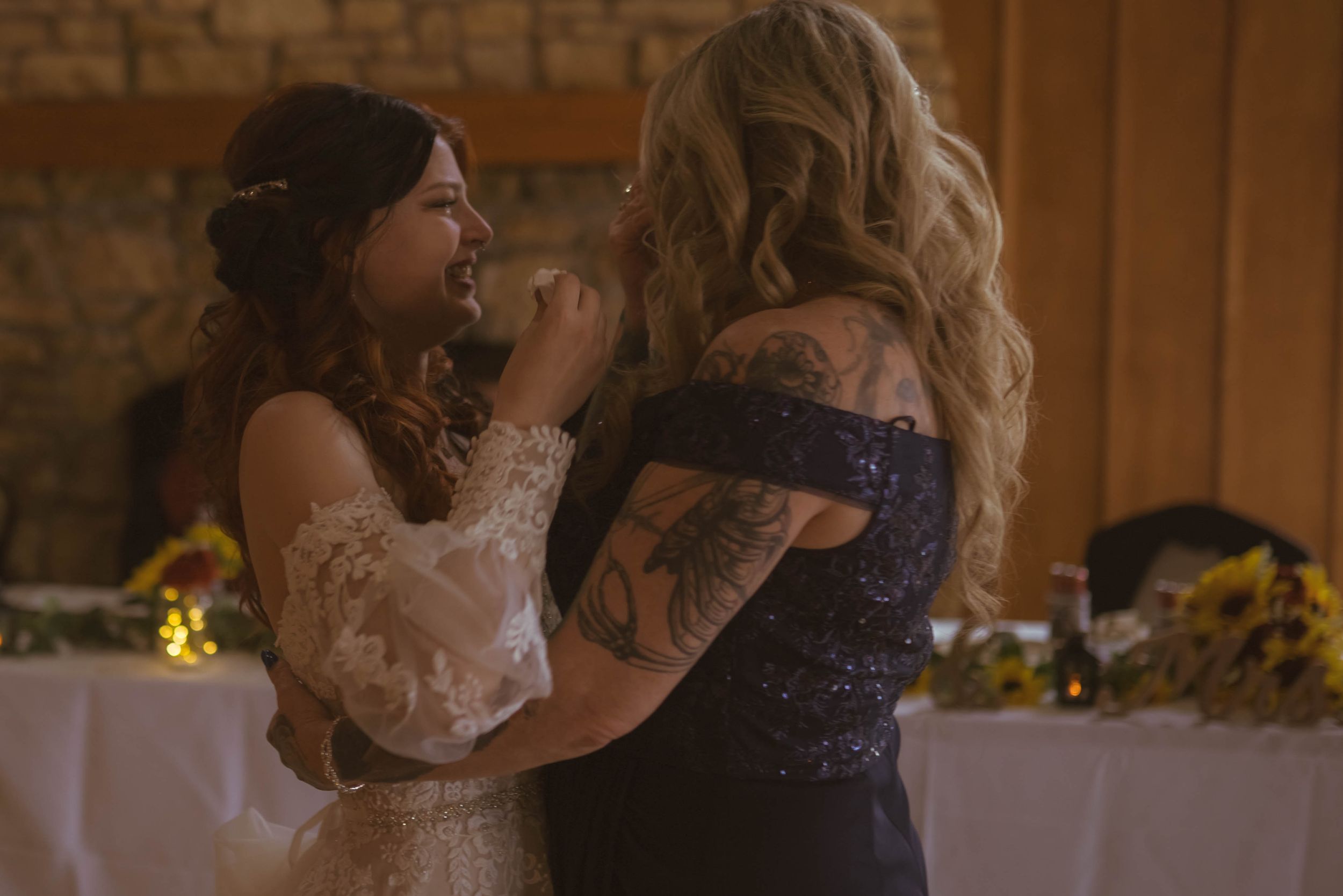 Wedding reception venue features stone walls and elegant table settings with natural lighting.