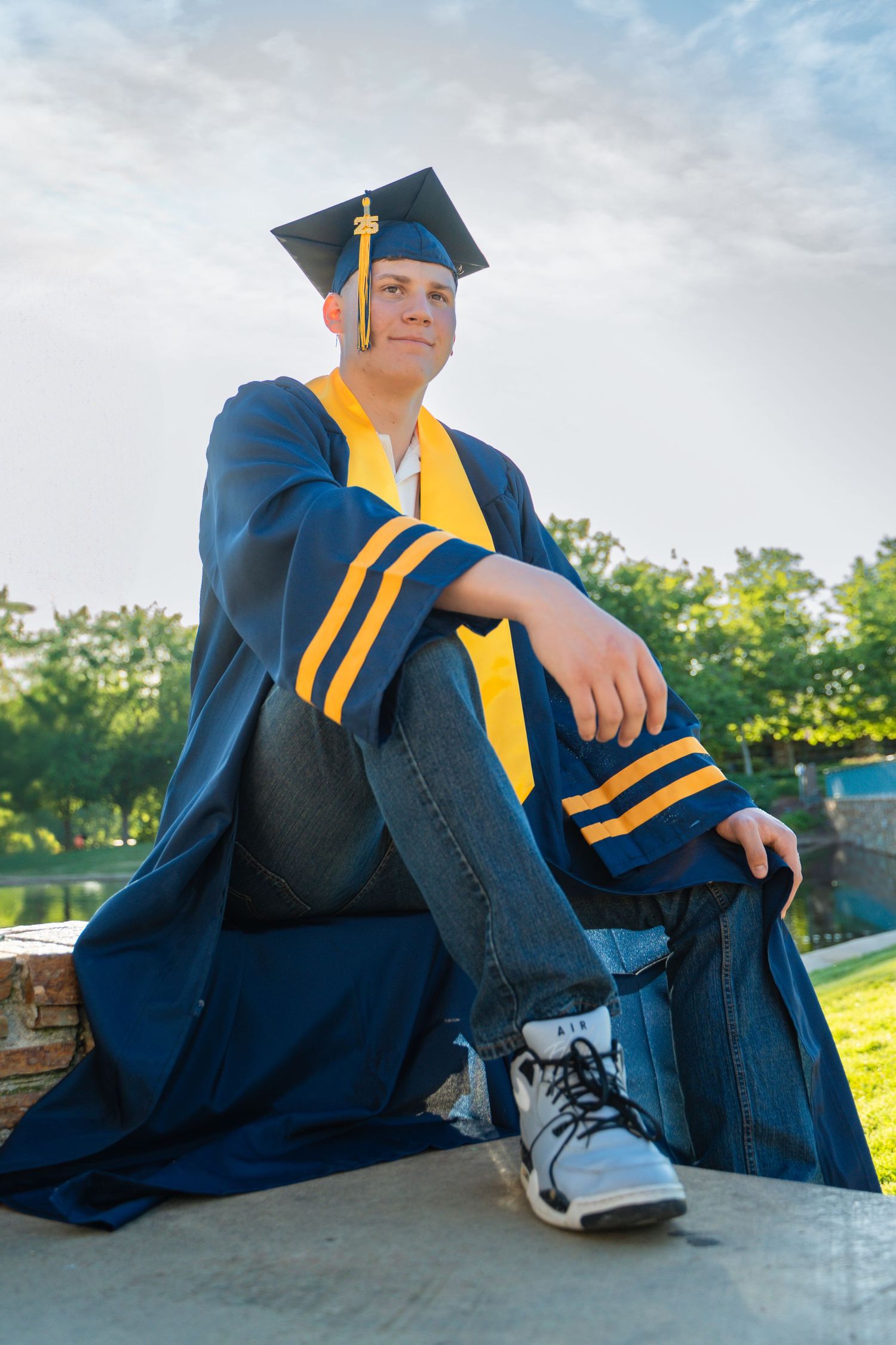 Senior graduation photos with person in blue cap and gown posed on outdoor ledge.