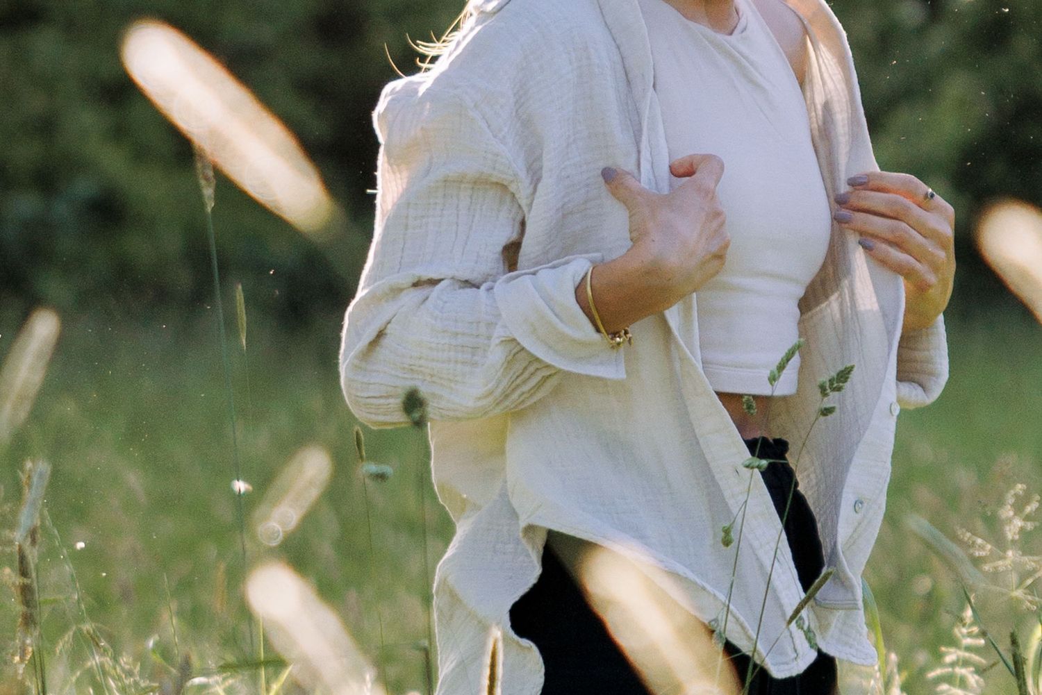 Playful dance movements in white clothing against a backdrop of wild grasses.