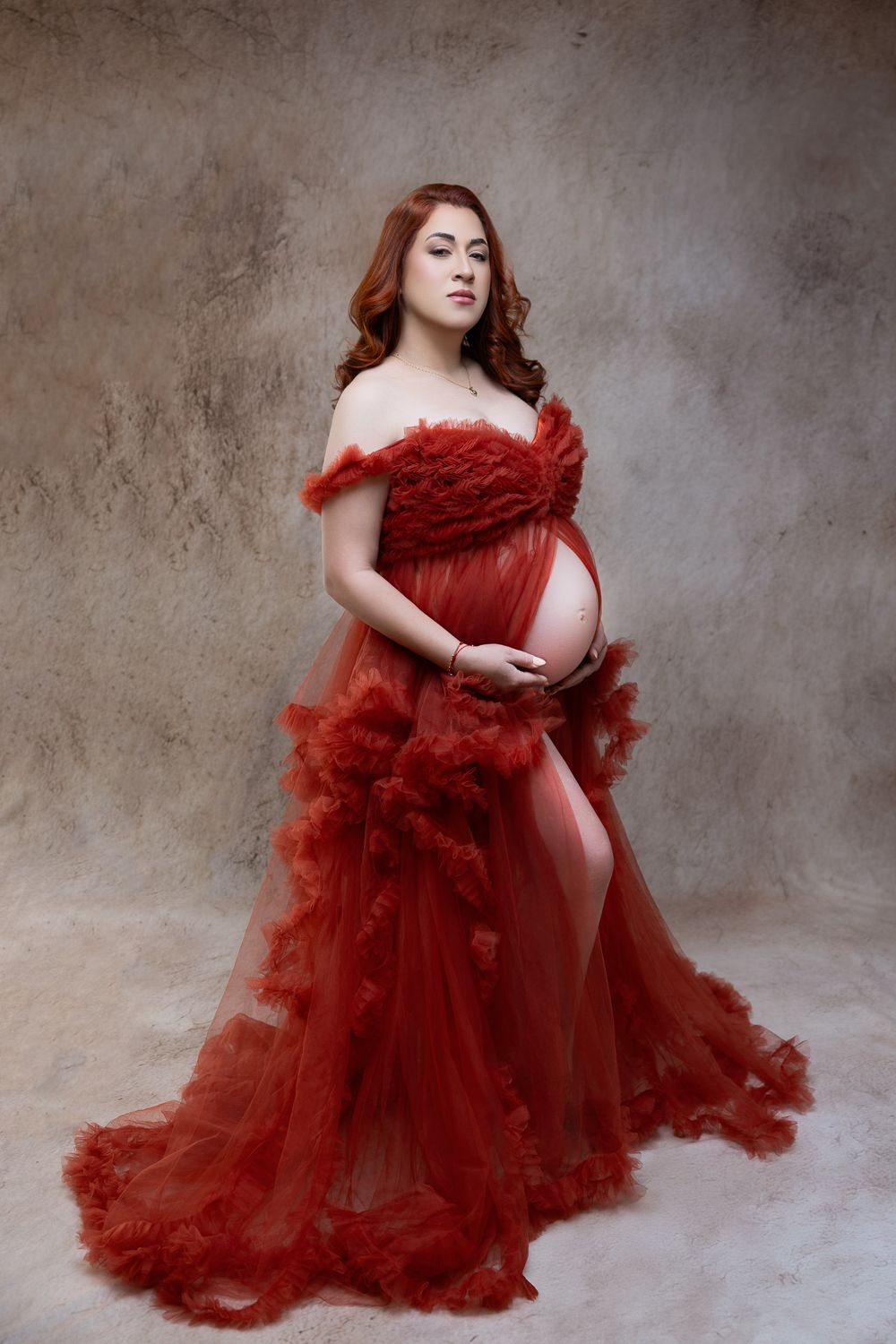 A series of artistic fashion photos showing a flowing deep red tulle gown against a textured gray backdrop.