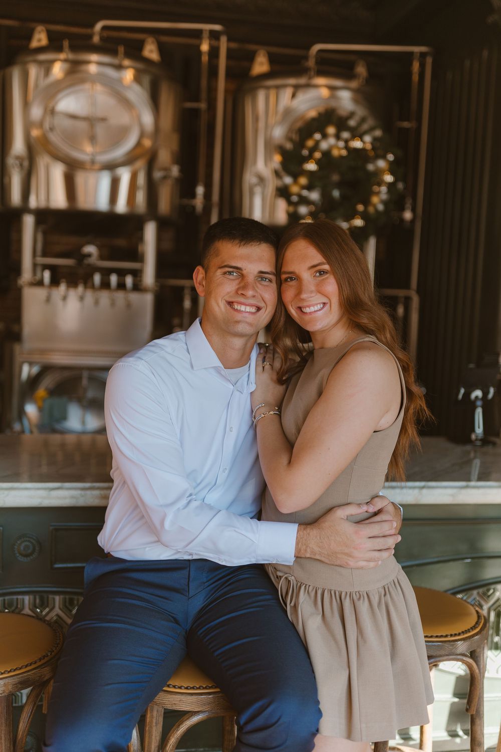A couple shares warm embraces and smiles while sitting at a bar counter with elegant decor in the background.