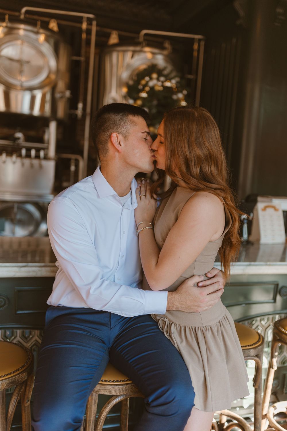 A romantic couple embraces at a cozy bar interior with rustic decor and warm lighting.