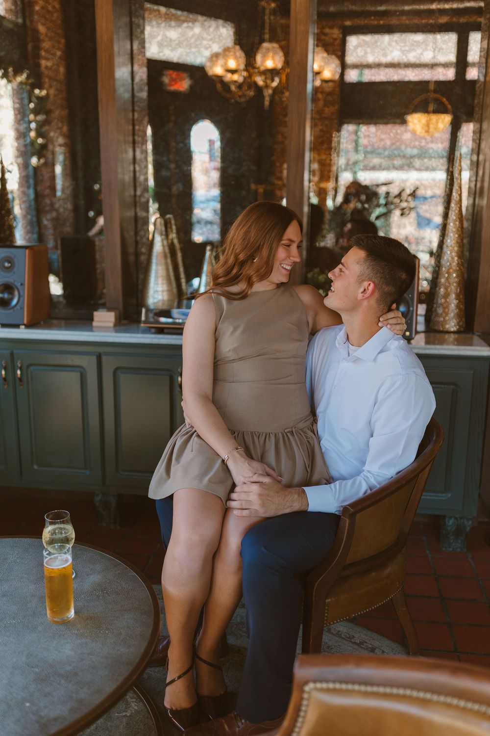Romantic couple shares intimate moment in rustic bar setting with brick walls and vintage decor.