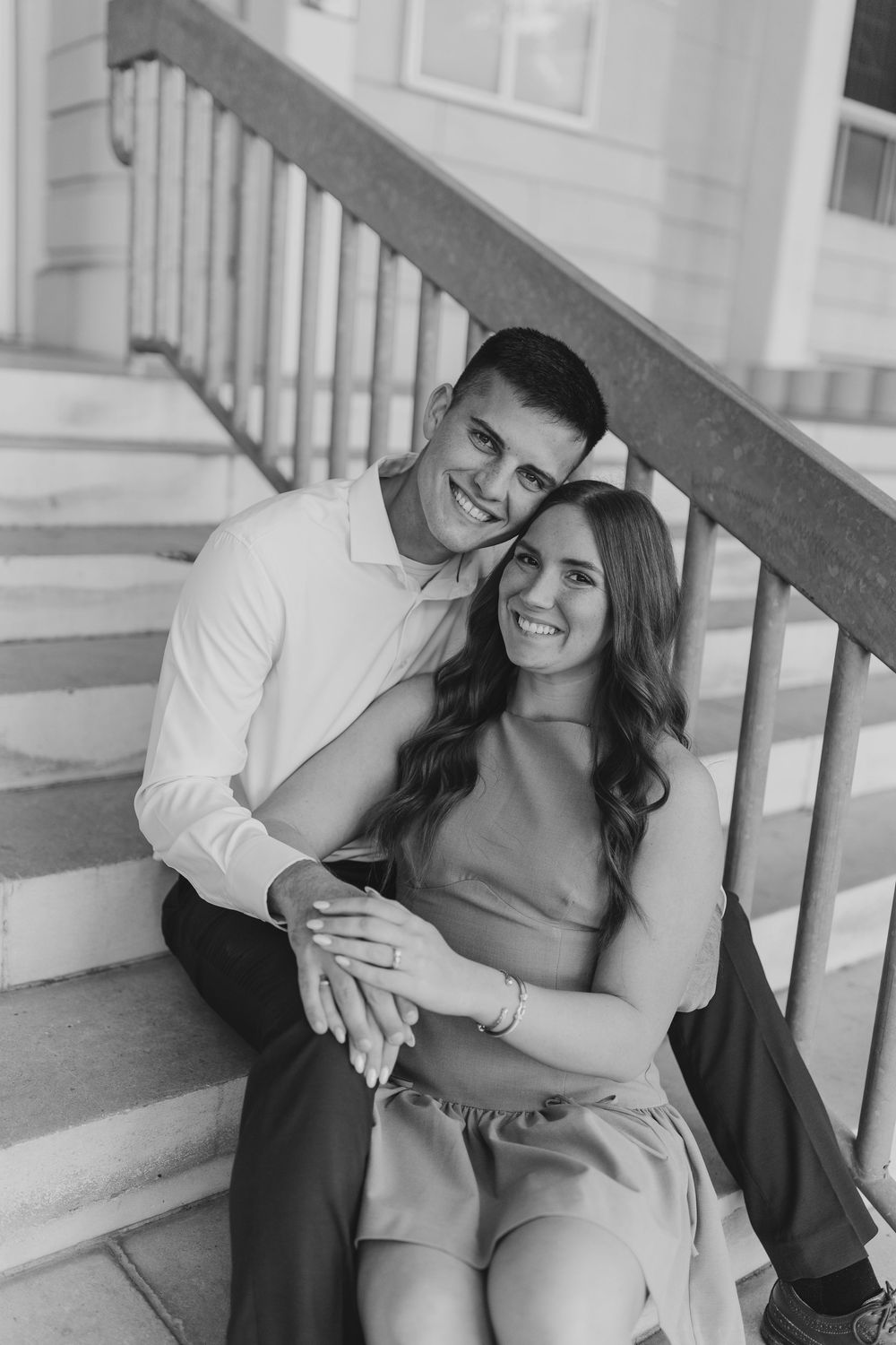 Black and white portrait of a happy couple embracing on outdoor steps.
