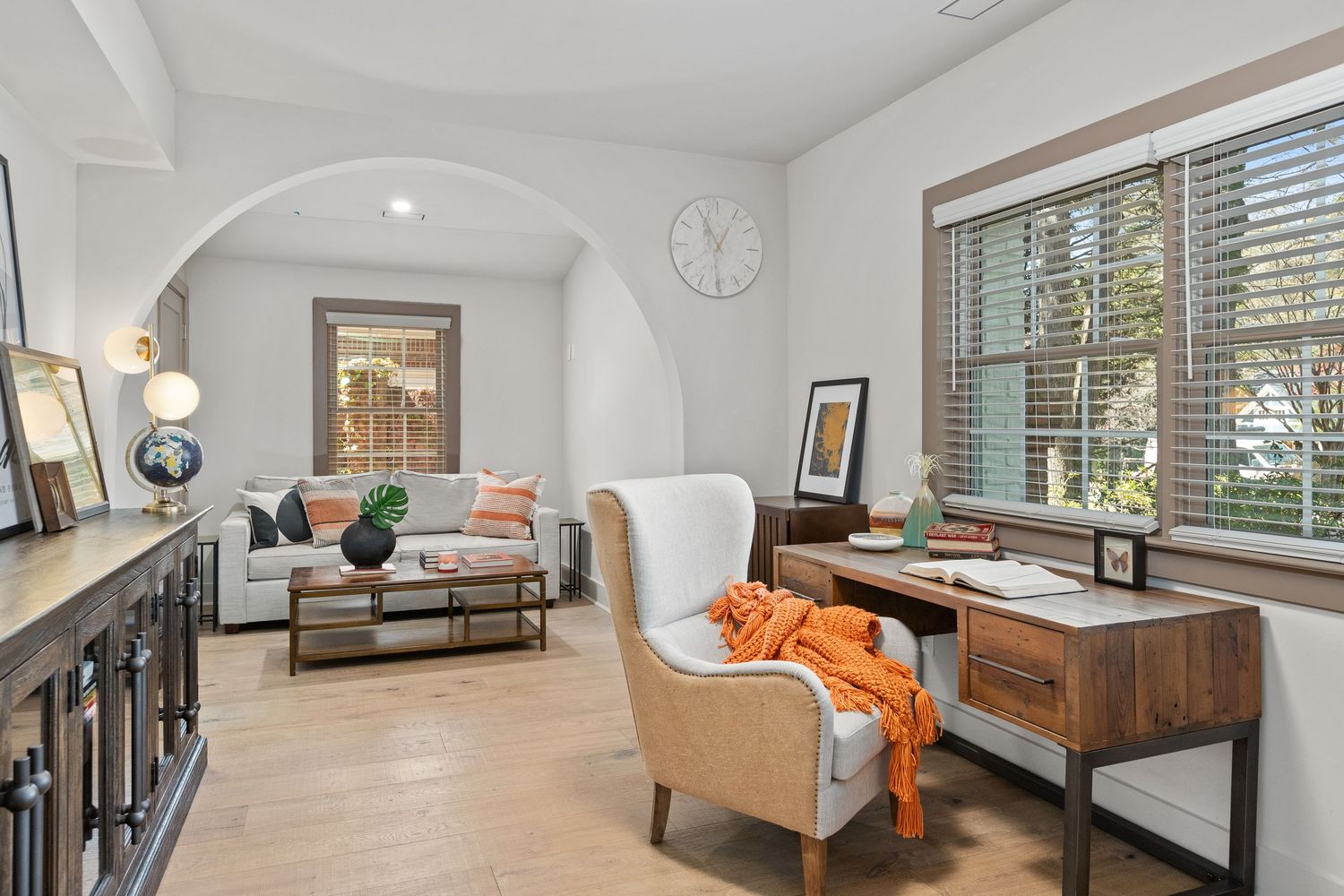 Modern Mediterranean style study with arched doorway, light wood floors, neutral tones and orange accents. Real estate photography.