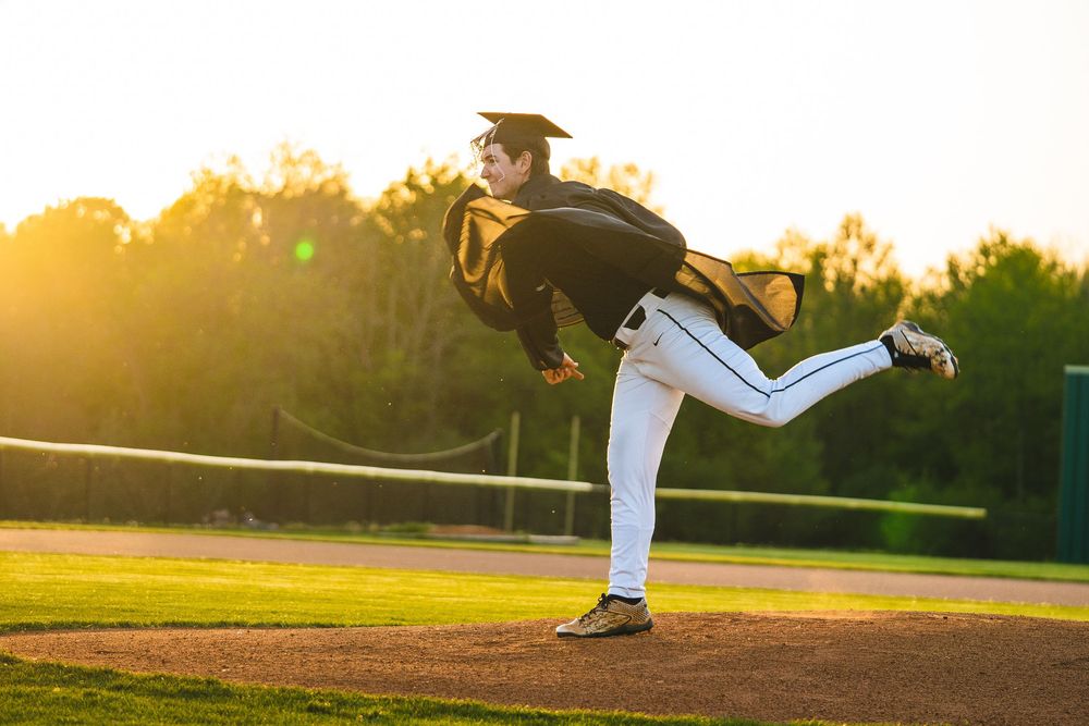Baseball pitcher follows through on delivery during sunset practice on baseball field with dramatic golden lighting.