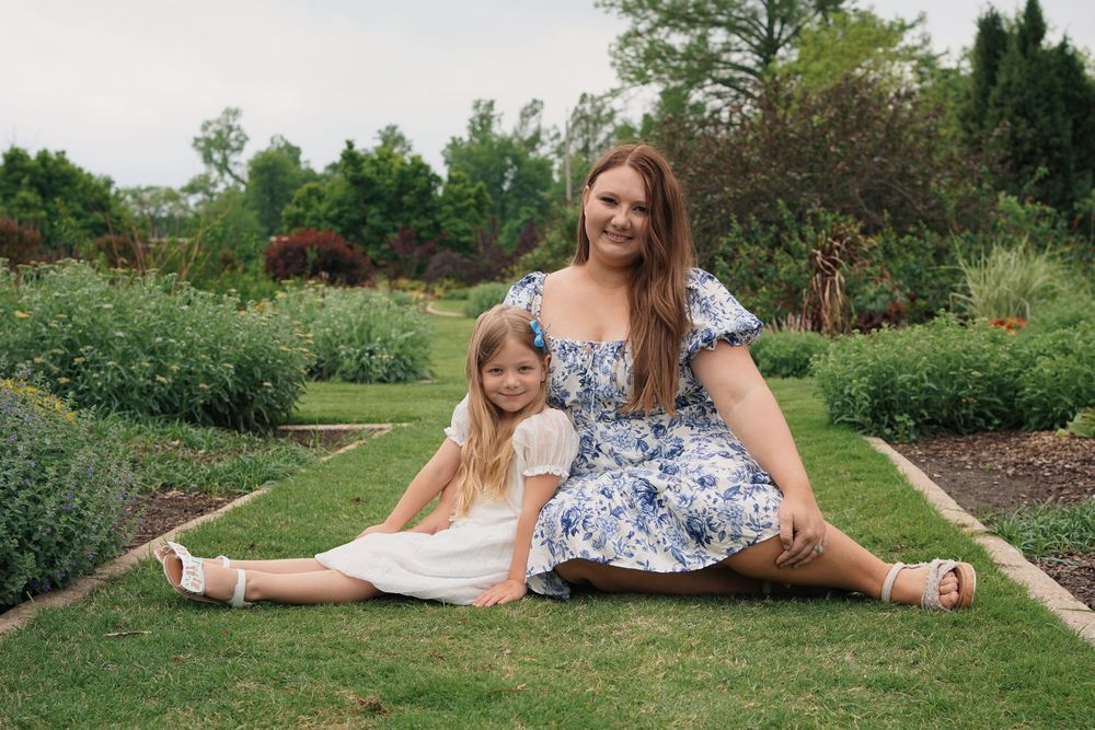 People enjoying a sunny summer day relaxing in a lush green garden with blooming flowers in the background.