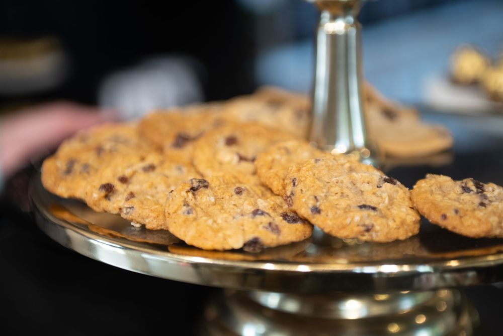 Freshly baked chocolate chip cookies displayed on a silver cake stand with shallow depth of field.