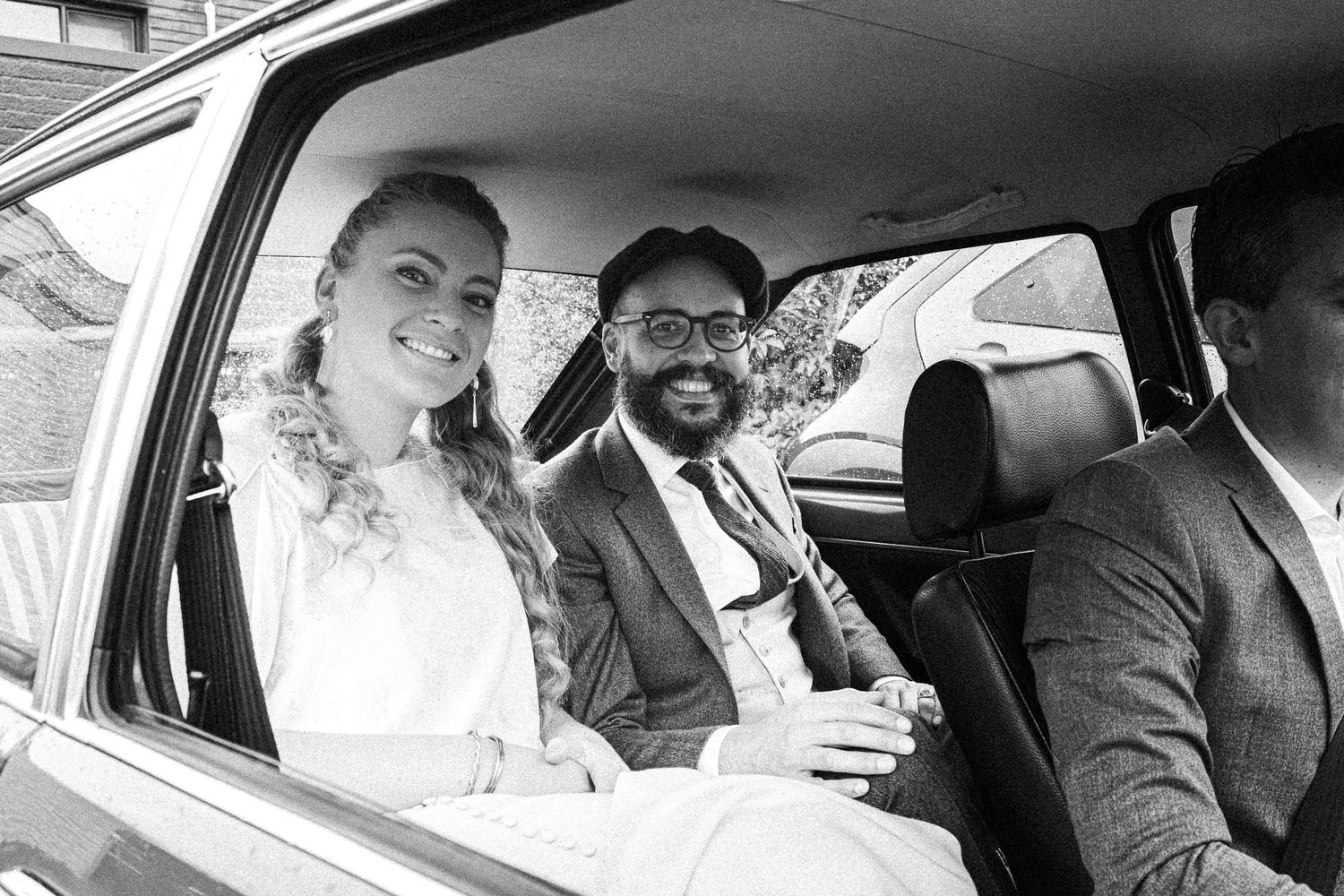 Black and white candid photos of a couple sharing joyful moments in their wedding car.