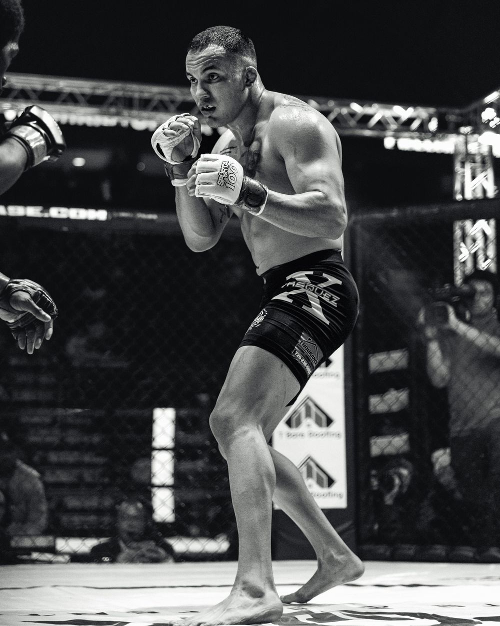 Two MMA fighters engage in ground grappling during a professional match in an octagon cage setting.