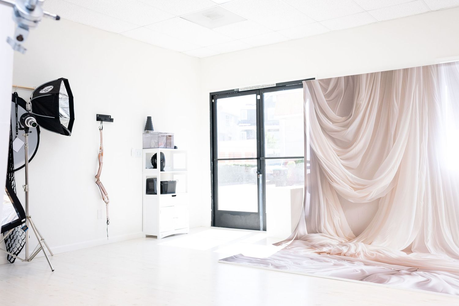 Photography studio with lighting equipment and flowing fabric drapes against white walls.