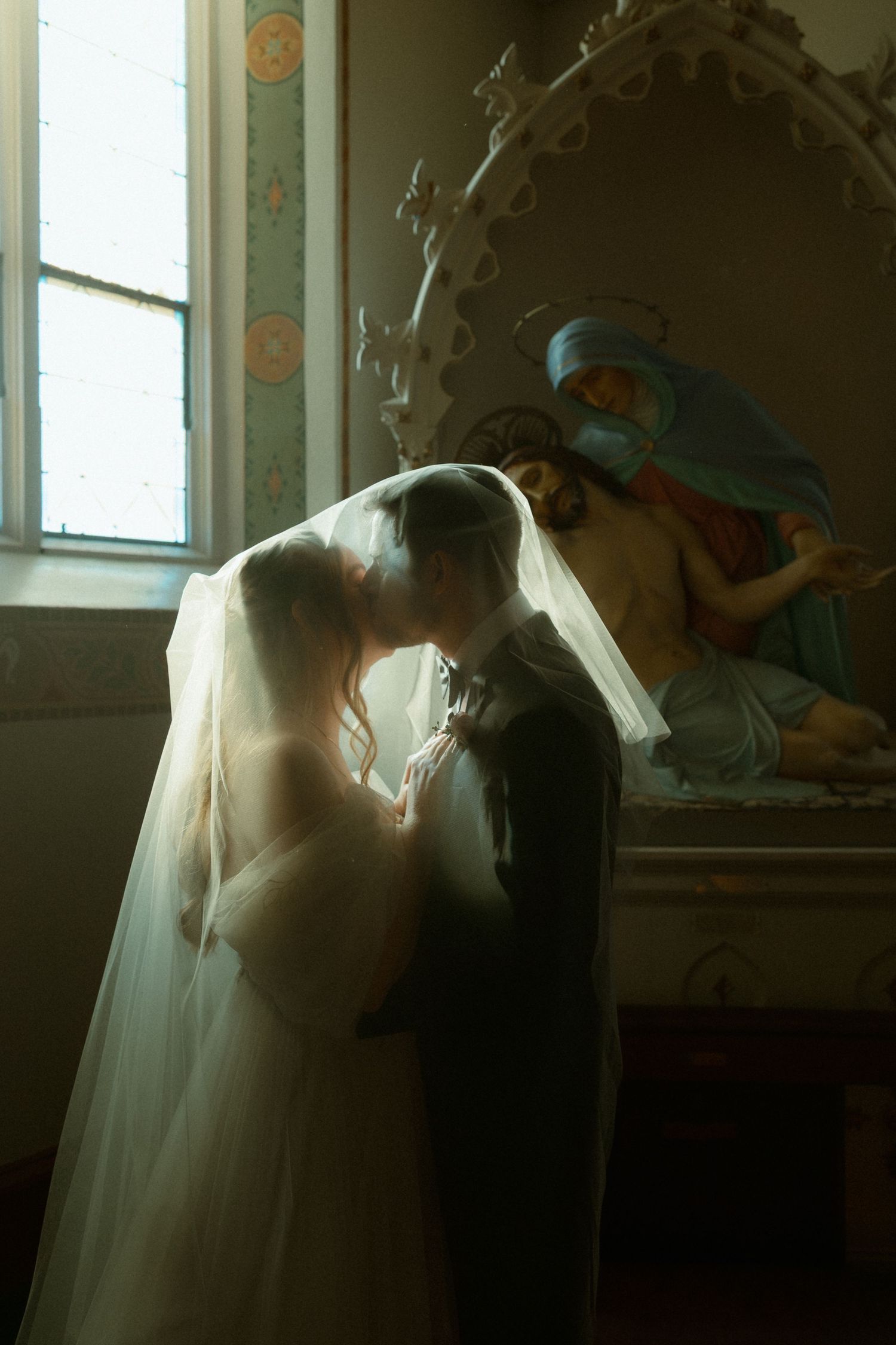 Close-up of newlyweds holding hands showing wedding rings in natural sunlight.