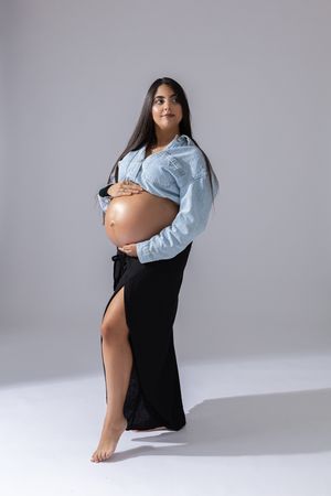 Artistic maternity portraits featuring denim shirt and black dress against minimalist grey backdrop.