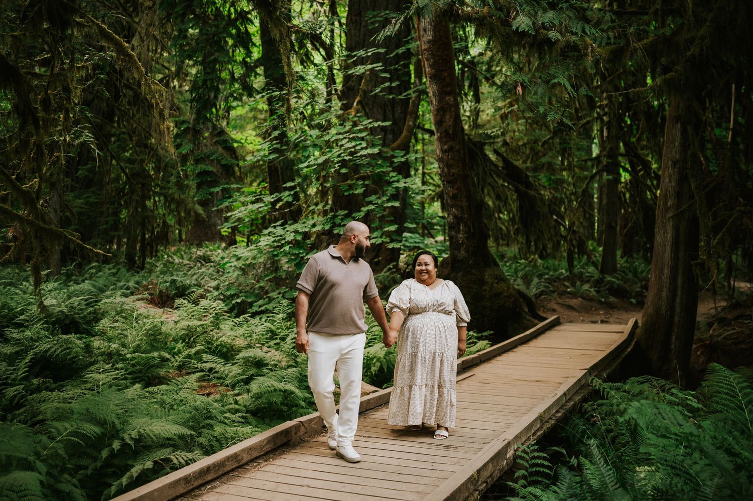 Photoshoot of engaged couple walking in Cathedral Groves, MacMillan Park forest amongst ferns firs. Vancouver Island adventure photographer
