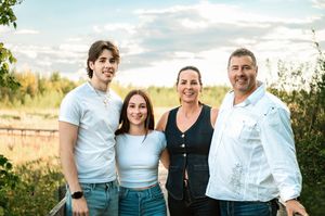 A joyful family group poses together outdoors against a scenic natural backdrop during golden hour.