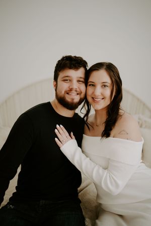 Romantic couple in black and white outfits embracing in soft lighting.