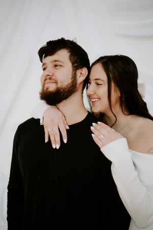 Artistic engagement photos showing tender moments between couple against white studio background.