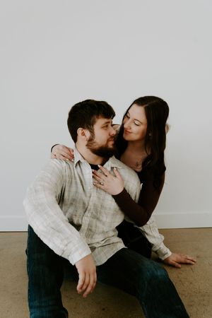 Couple sharing passionate moments during casual photo session on studio floor.