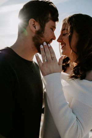 Backlit couple sharing tender moment in dramatic lighting against white backdrop.