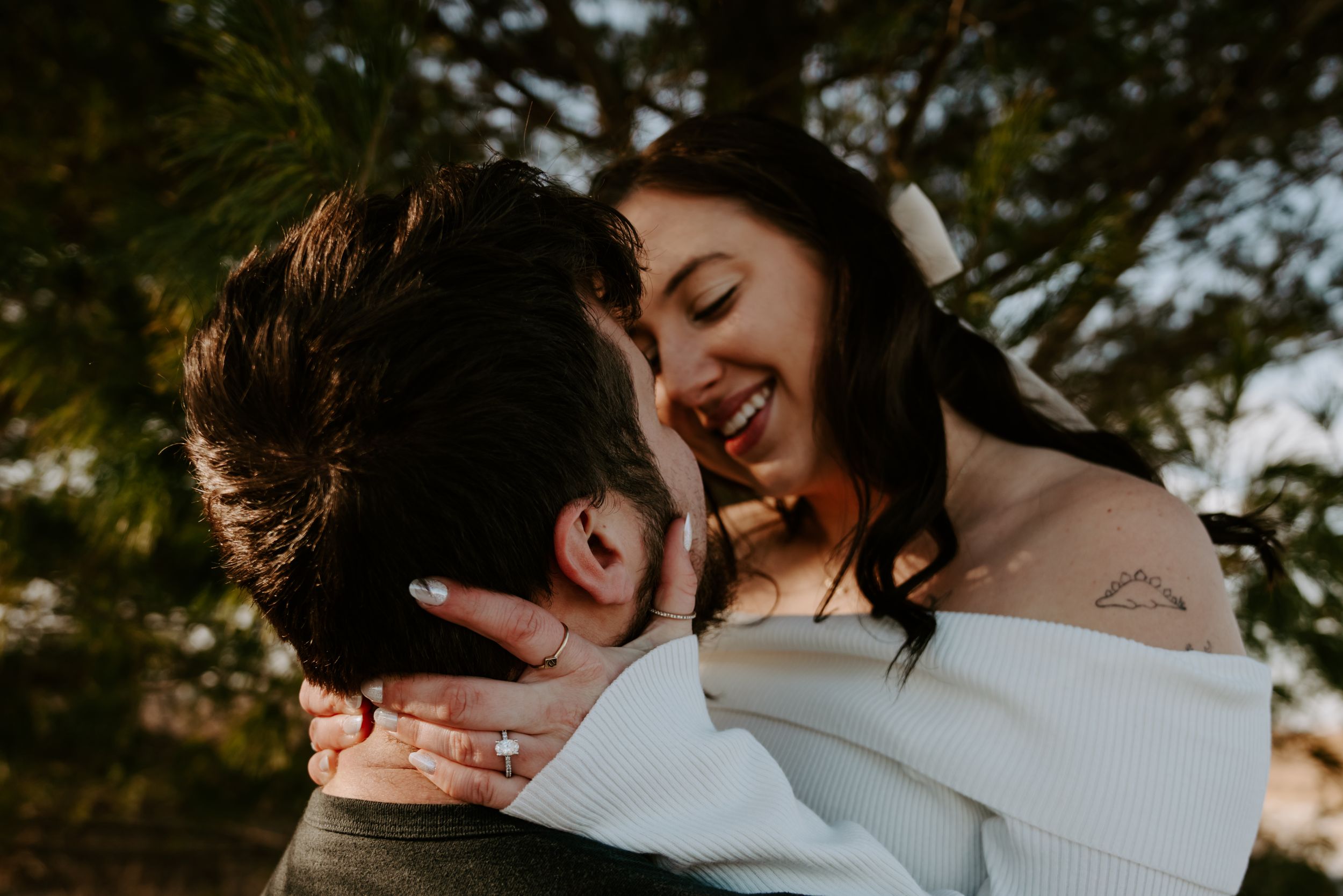 Romantic outdoor photoshoot with couple in white and dark clothing against natural backdrop.