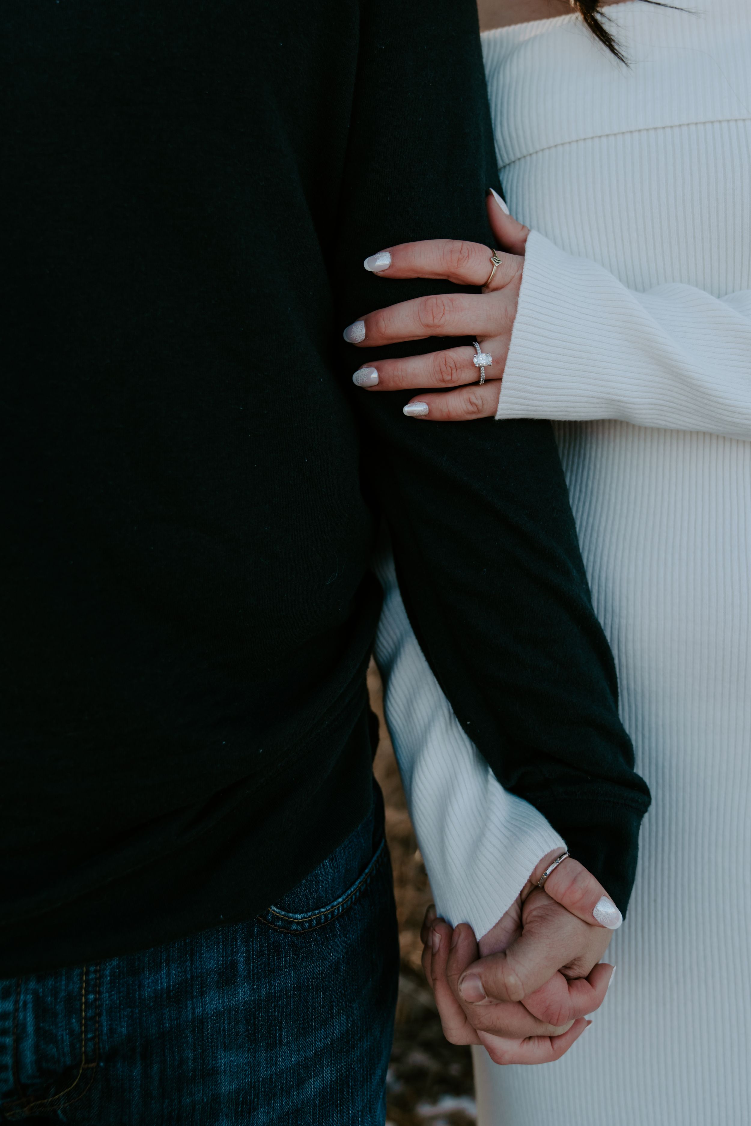 Close-up of hands and clothing details showing white sweater against dark fabric.