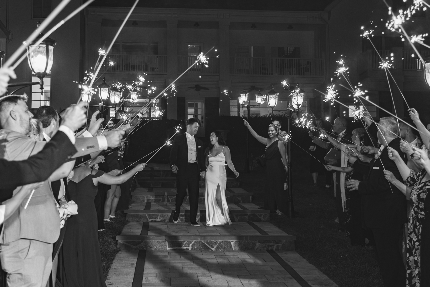 Wedding guests hold sparklers creating a magical exit tunnel for the newlyweds.