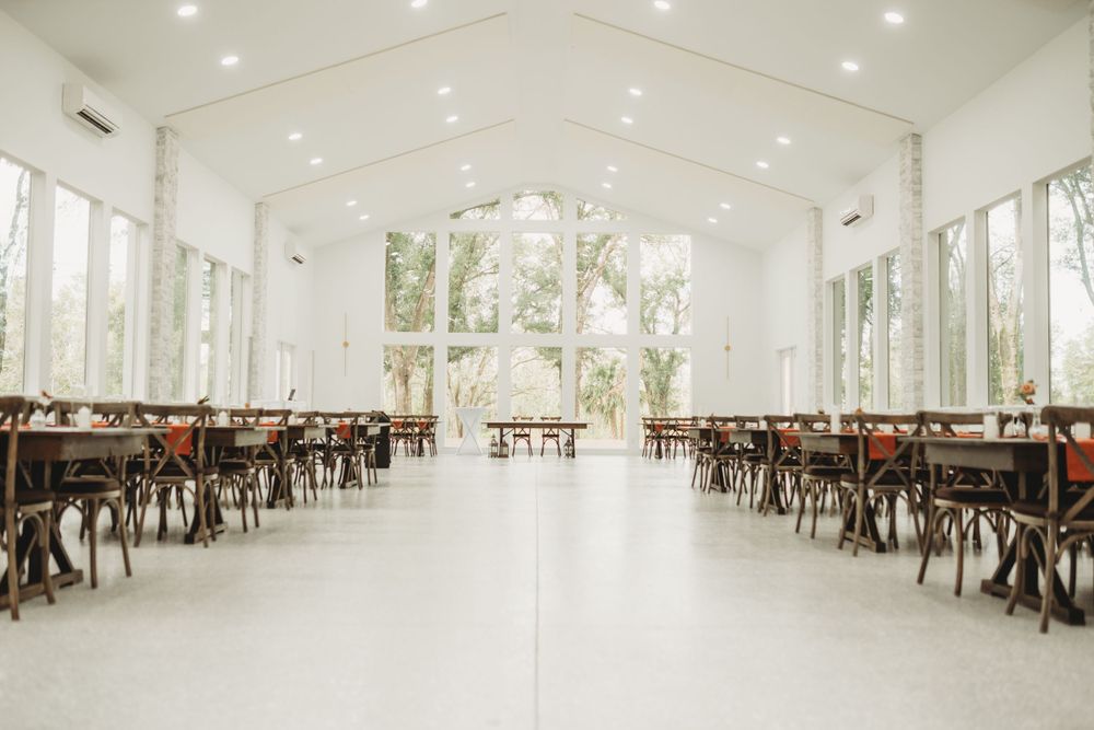A bright white modern reception venue with cross-back chairs and large windows.