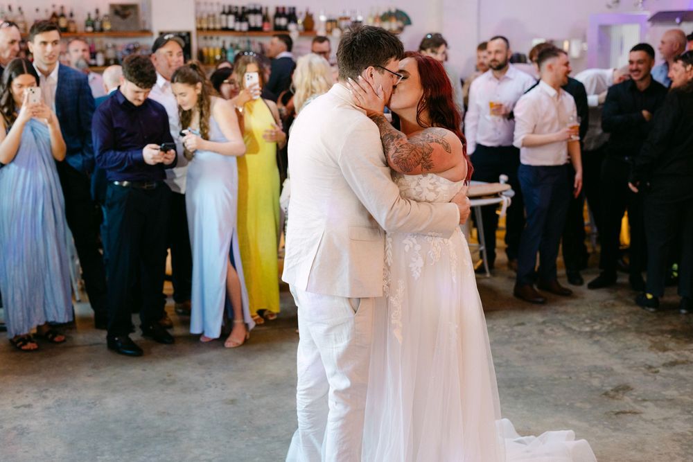 Wedding guests gather around a dance floor as a couple shares their first dance at an elegant reception celebration.