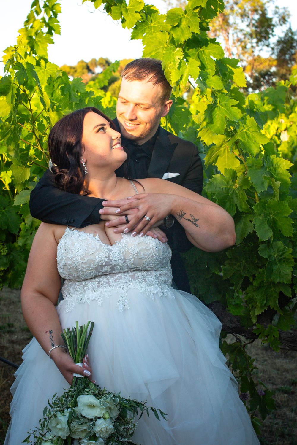 A joyful embrace among vineyard vines during golden hour.